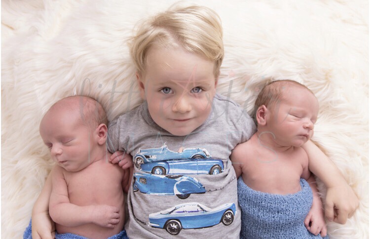 A toddler and newborn baby twins in a photoshoot