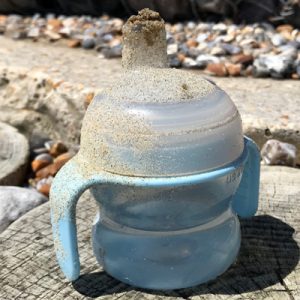 A sippy cup covered in sand