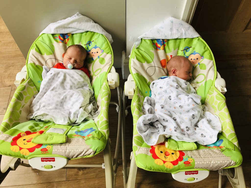 Tiny newborn twins asleep in bouncers