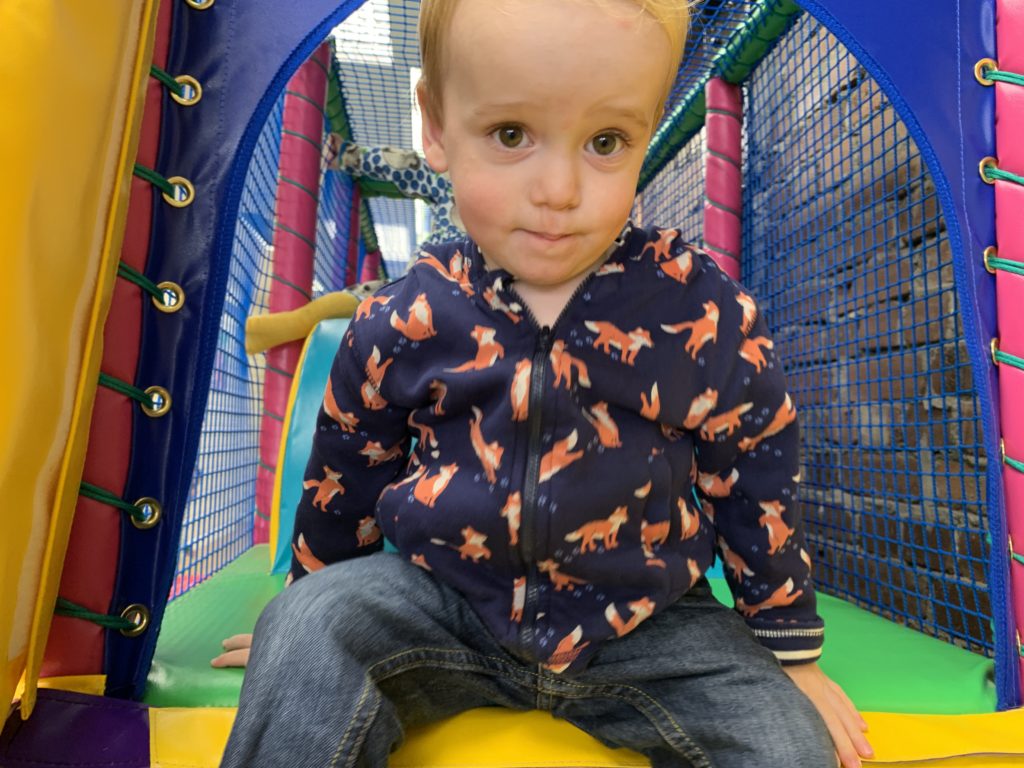 Toddler at the top of a soft play slide