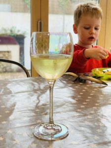 Thomas eating fish fingers whilst mum drinks a glass of wine