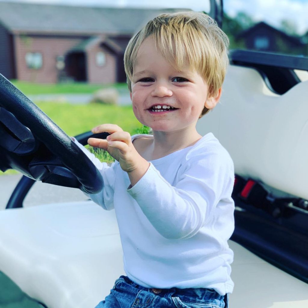 Toddler pretending to drive a golf buggy