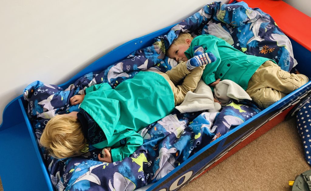 Twins ready for the school run but collapsed on big brother's bed