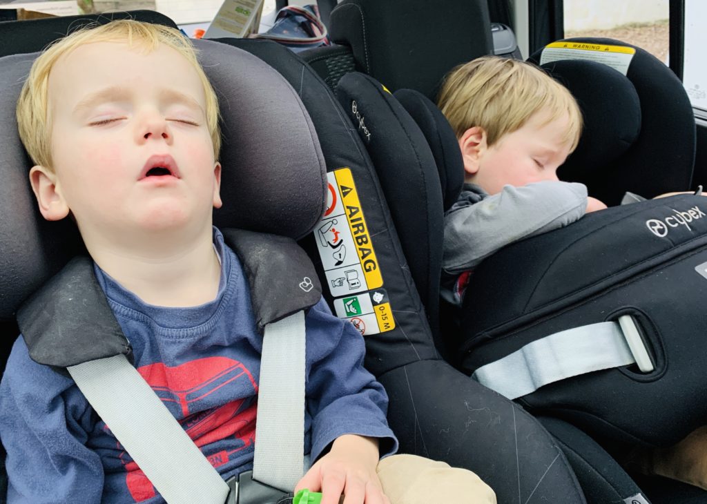 Twins sleeping in the car after the baby milestone of giving up the nap