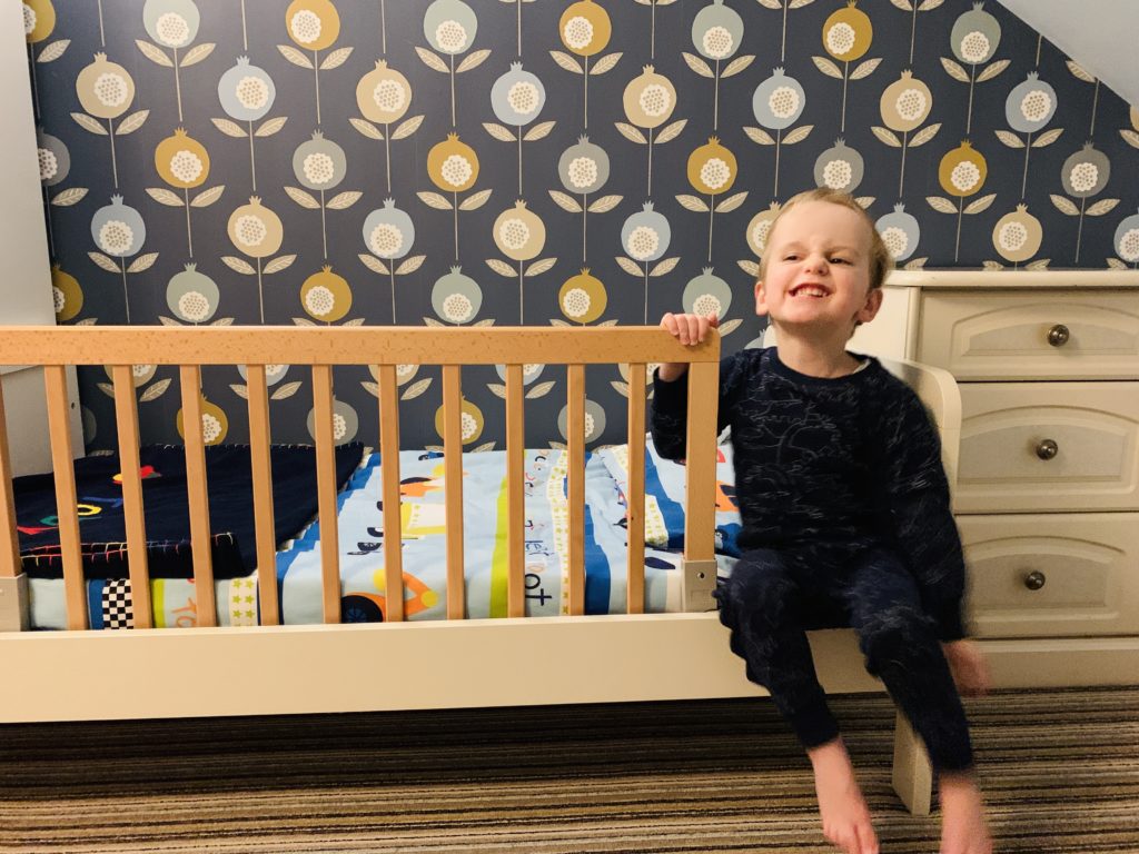 Toddler on the edge of his bed with a Baby Dan rail