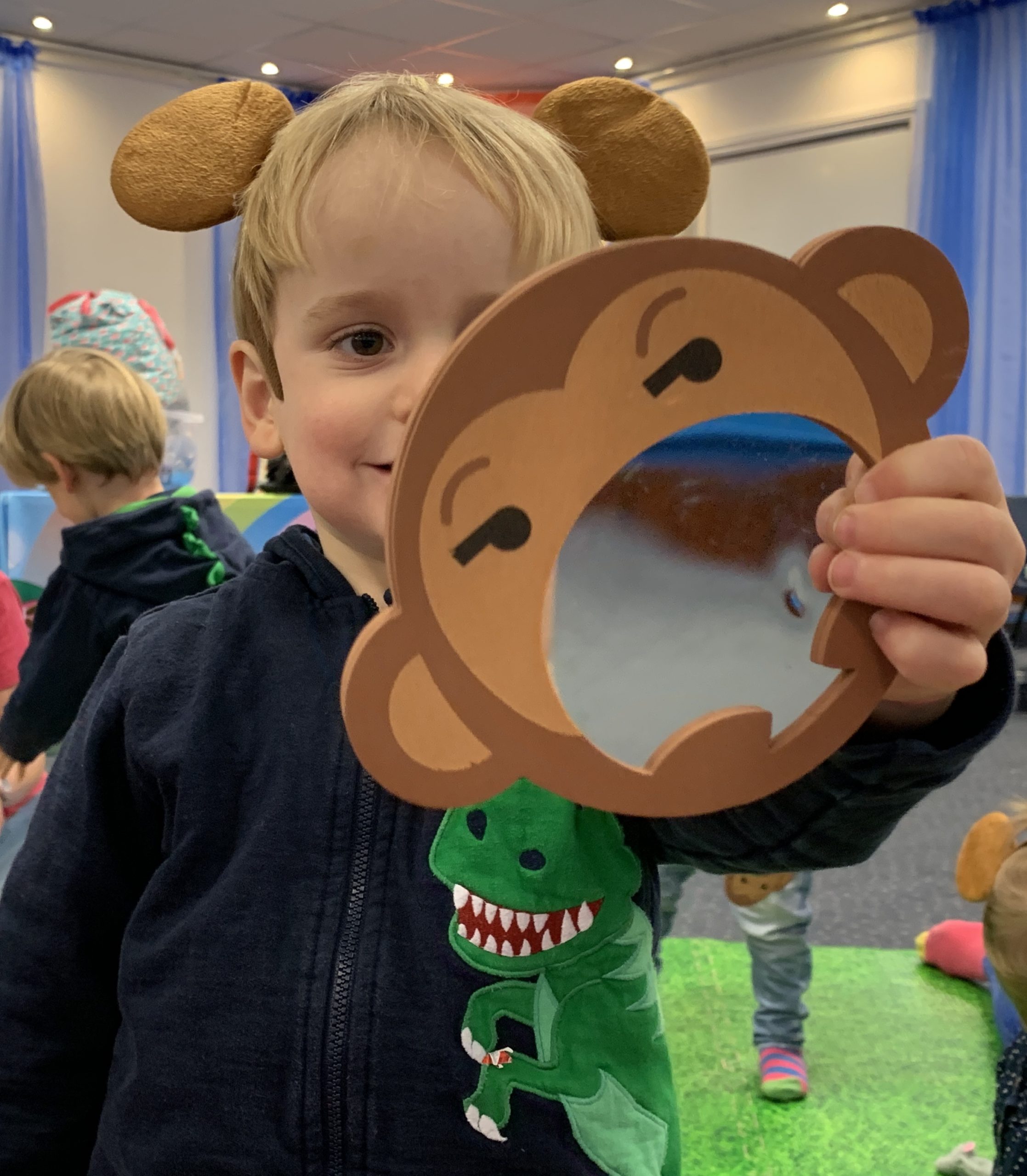 Toddler holding a mirror and wearing monkey ears