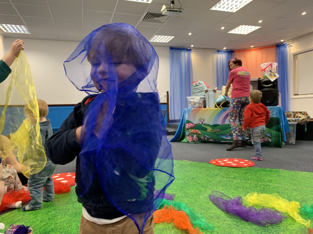 Toddler plays with a chiffon scarf at a baby group