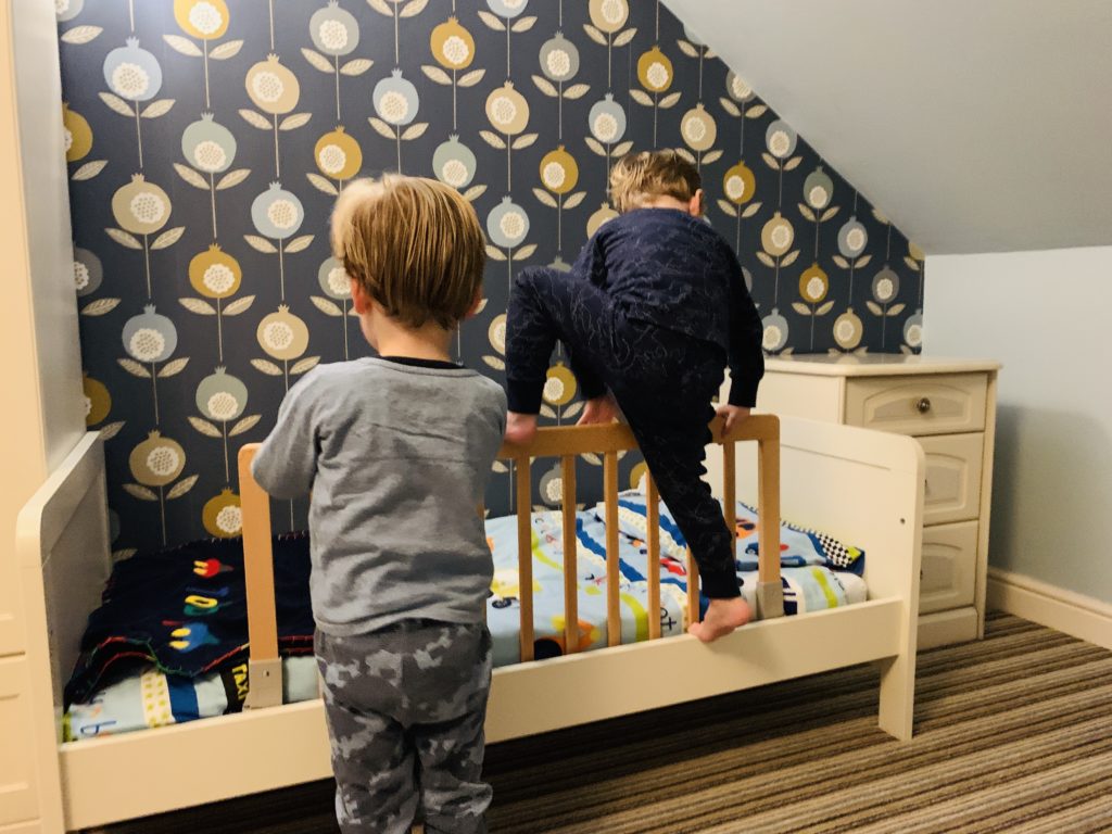 Twins climbing over bed rails