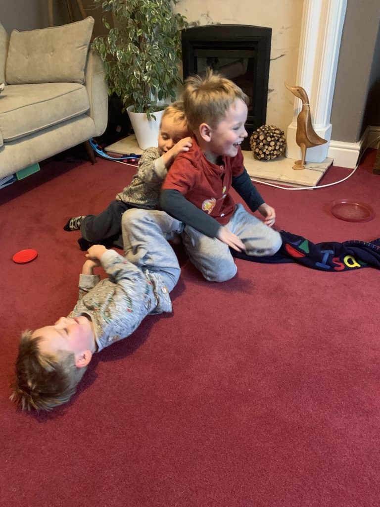 Twin toddlers and their brother play on the carpet