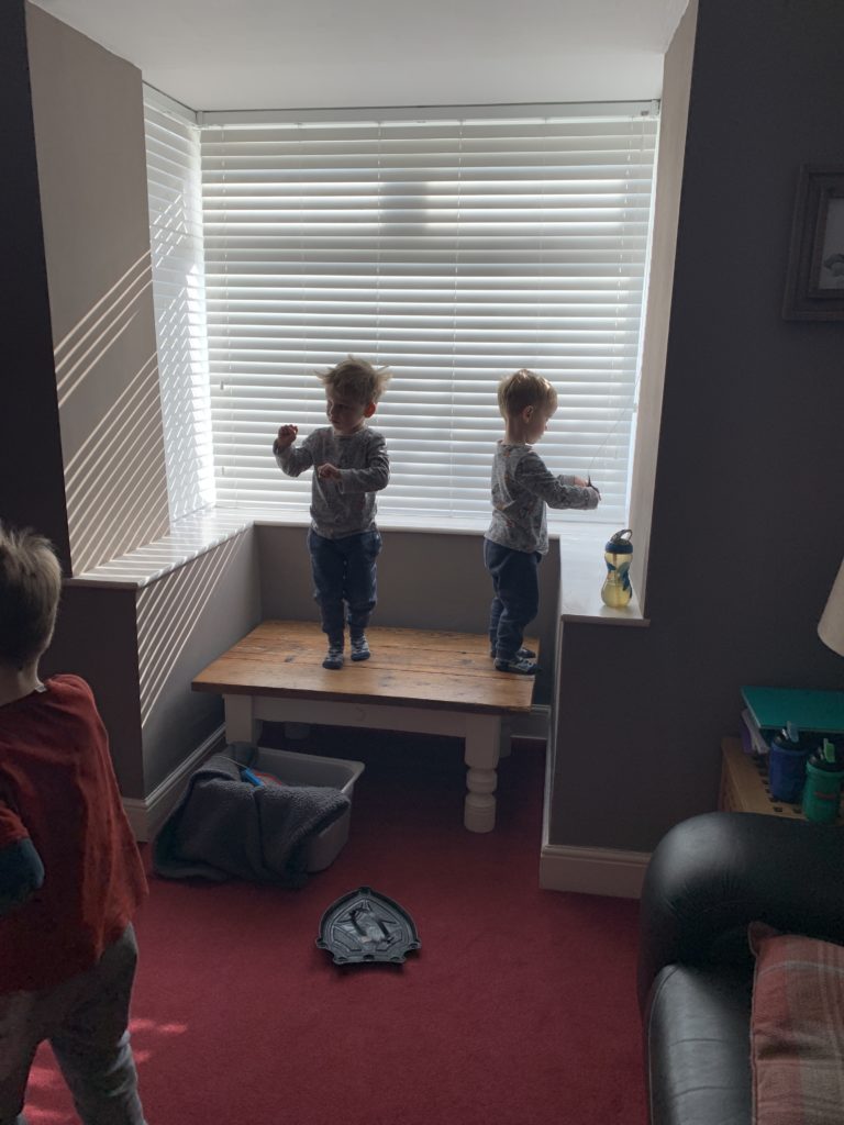 Twin toddlers stand on the coffee table 