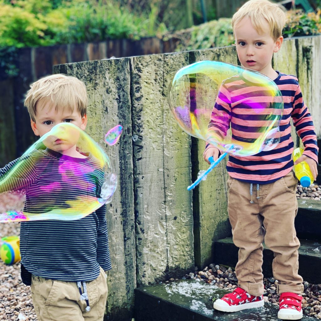 Twins play with giant bubbles during lockdown