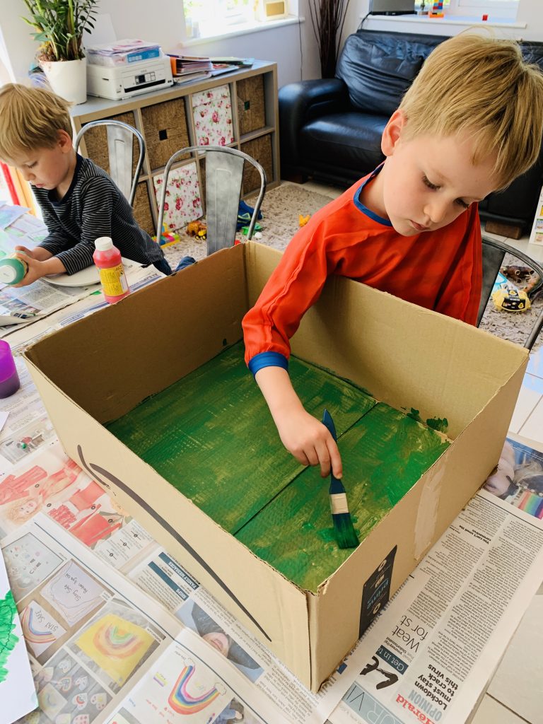 Four year old painting the inside of a cardboard box