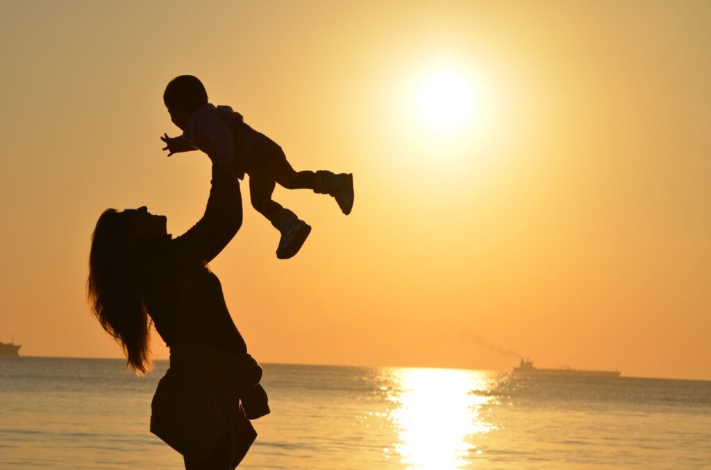 Travel influencer Mum and baby on a beach at sunset