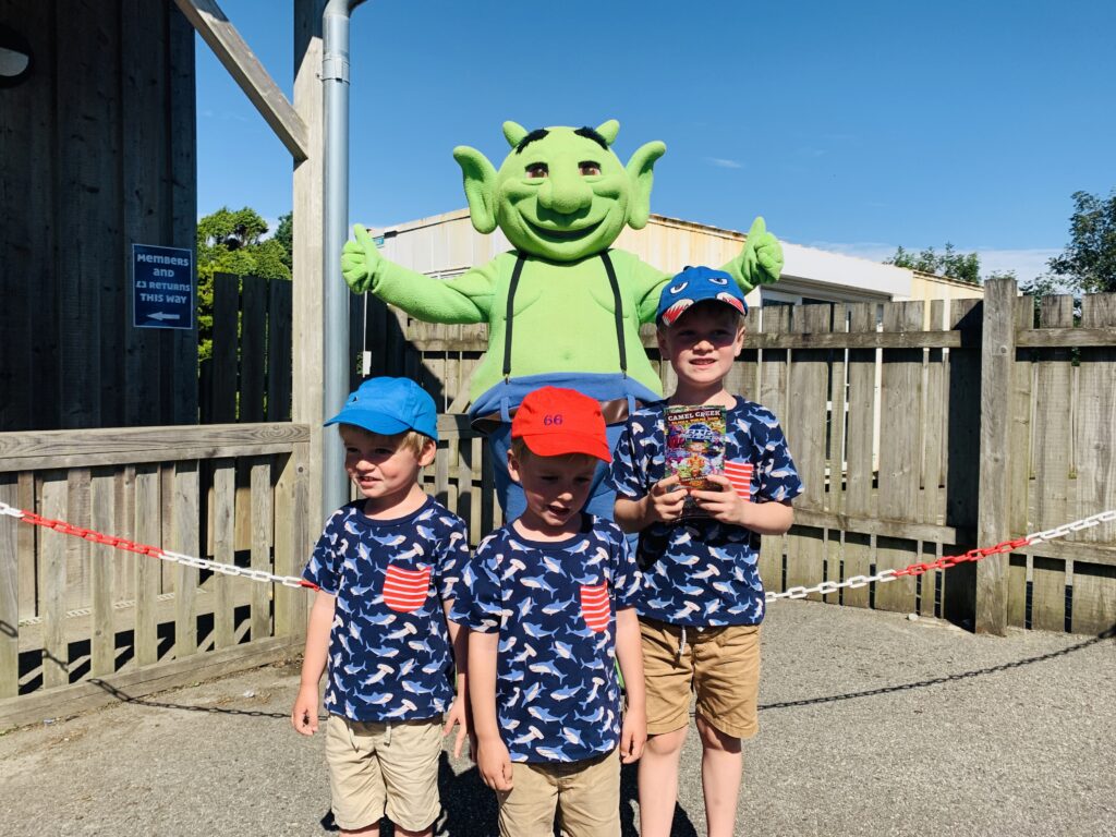 Three year old twin boys and five year old brother in front of Swampy the mascot at Camel Creek