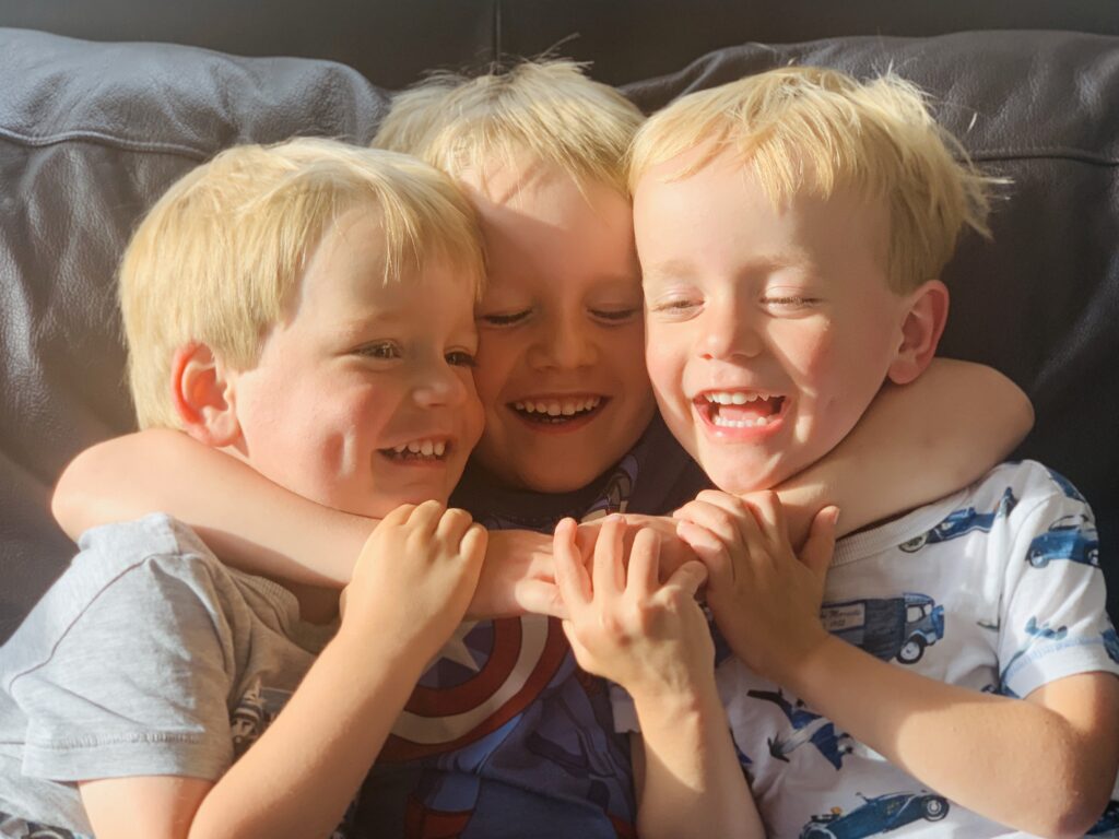 Three year old twins cuddled by five year old brother