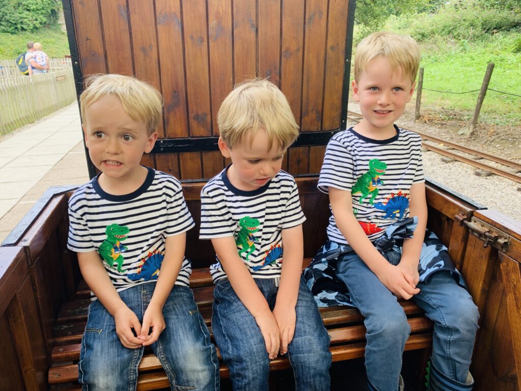 Three brothers sitting on a miniature steam train at Lappa Valley