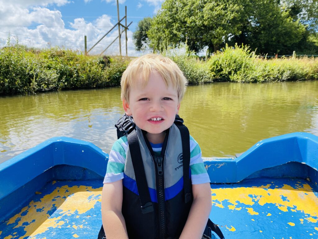 Three year old boy in a rowing boat on a boating lake at Springfields fun park
