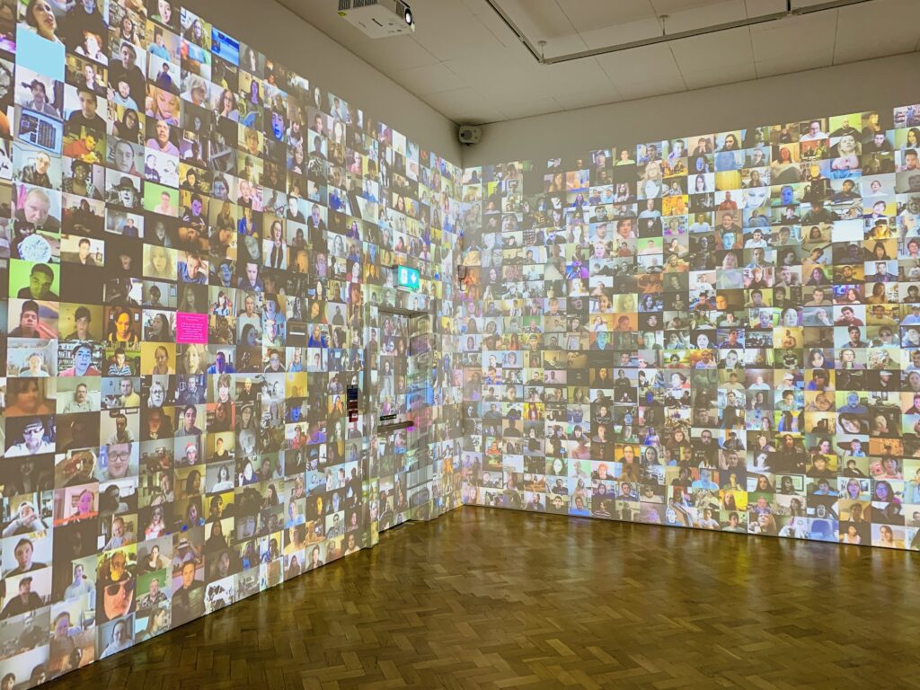 A room with all walls to ceiling covered in a digital display of moving images and faces at The Box in Plymouth