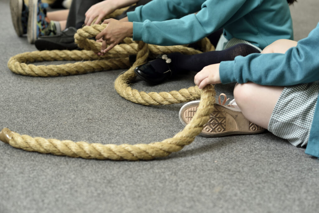 Close up picture of children's hands passing a rope as a part of an educational programme at The Box in Plymouth