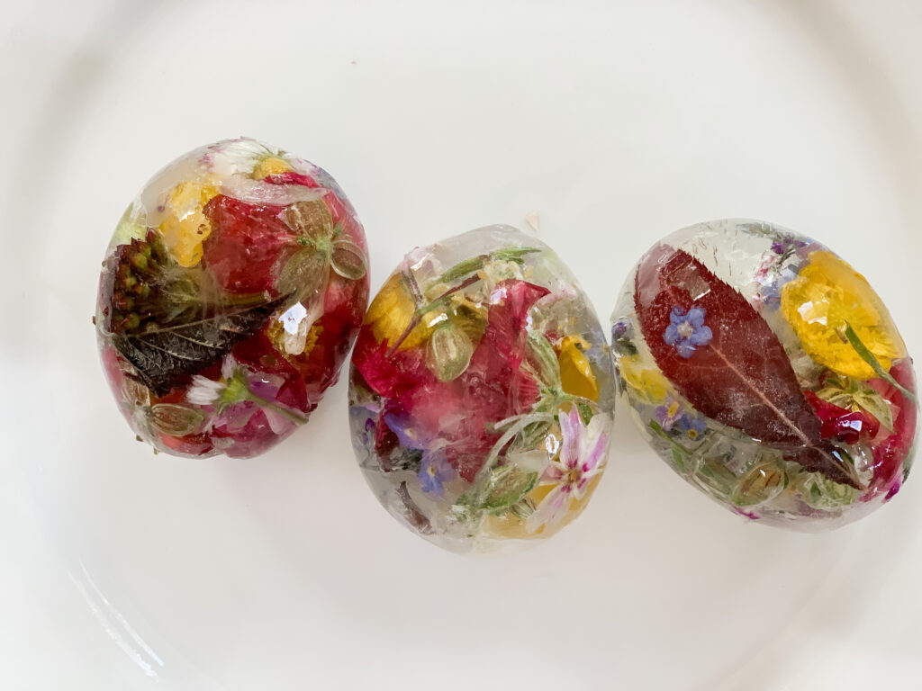 Colourful frozen eggs, which are egg shaped ice with colourful leaves and petals inside