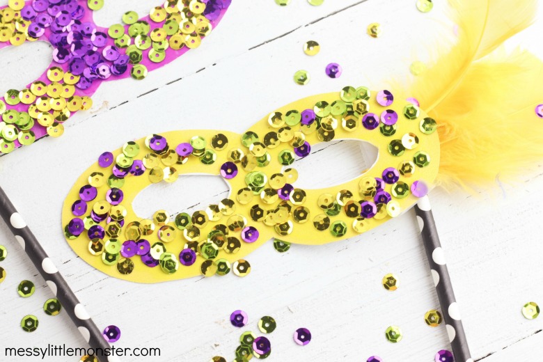 Yellow mardi gras mask decorated with sequins and glitter is a an easy craft idea for children