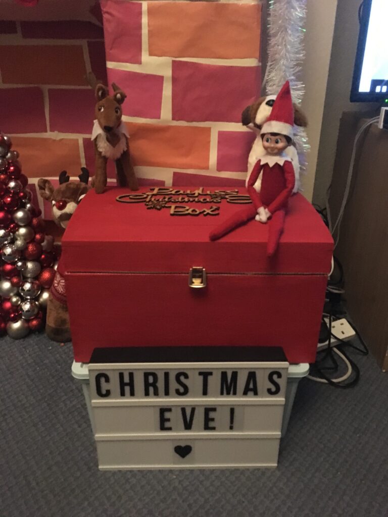 Elf toys on top of a Christmas eve box in front of the fire place