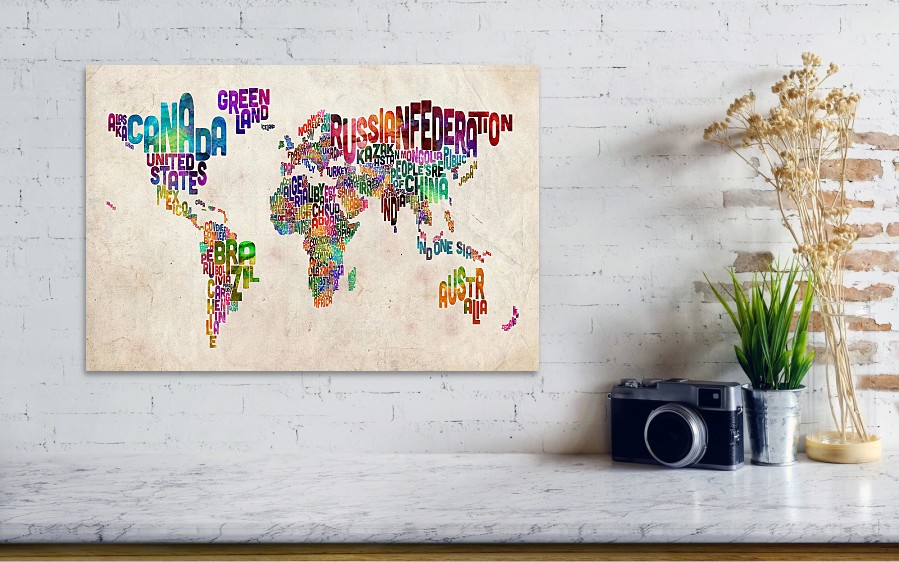 A grey wall and shelf with camera on it, with a map of the world picture on the wall. Countries on the map are made out of different words of countries