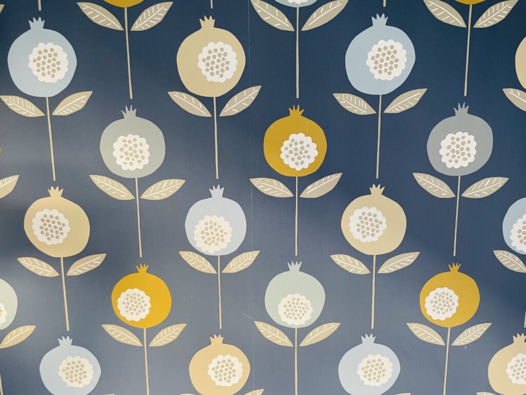 Blue wallpaper with mustard, beige and light blue flowers on it