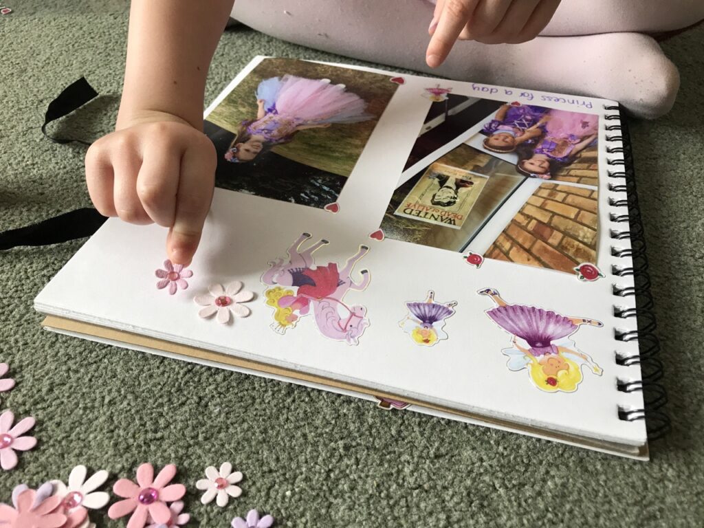 A girl's hand sticking stickers into a scrapbook around photos