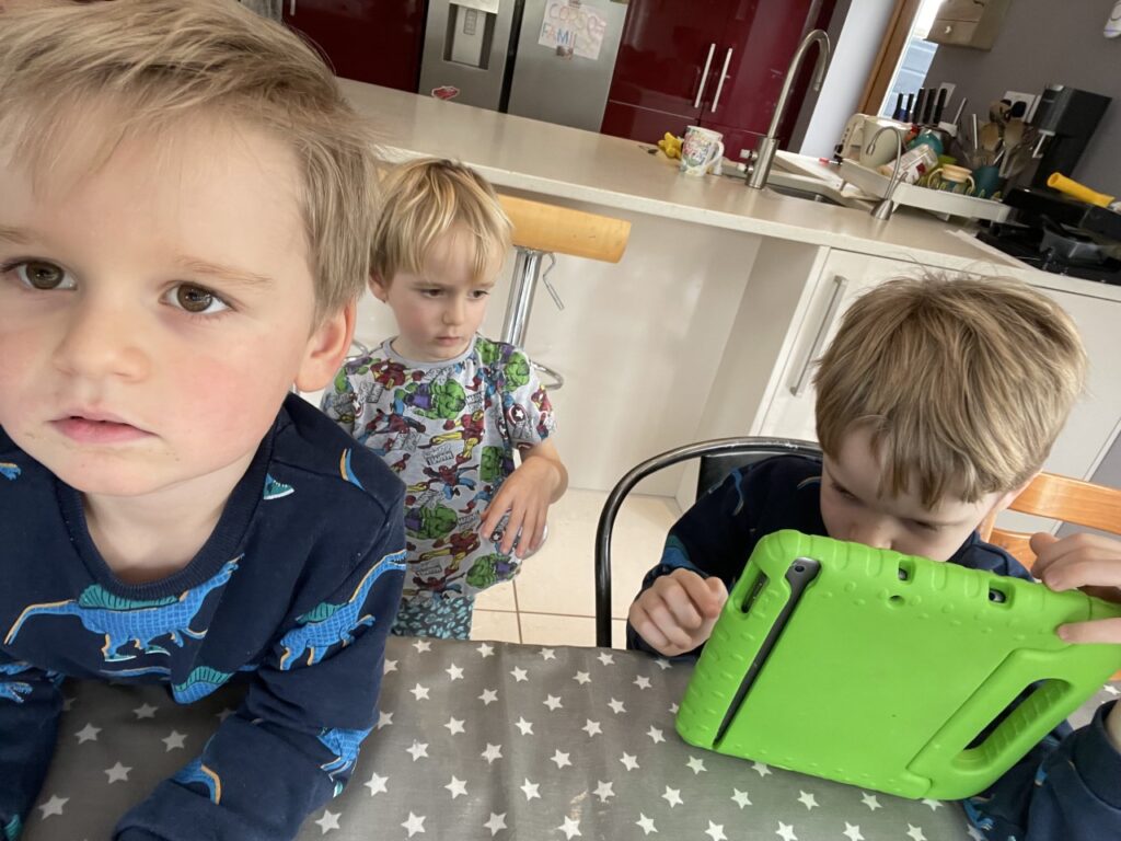 Three year old twin boys interrupting their homeschooling five year old brother trying to do maths on an iPad