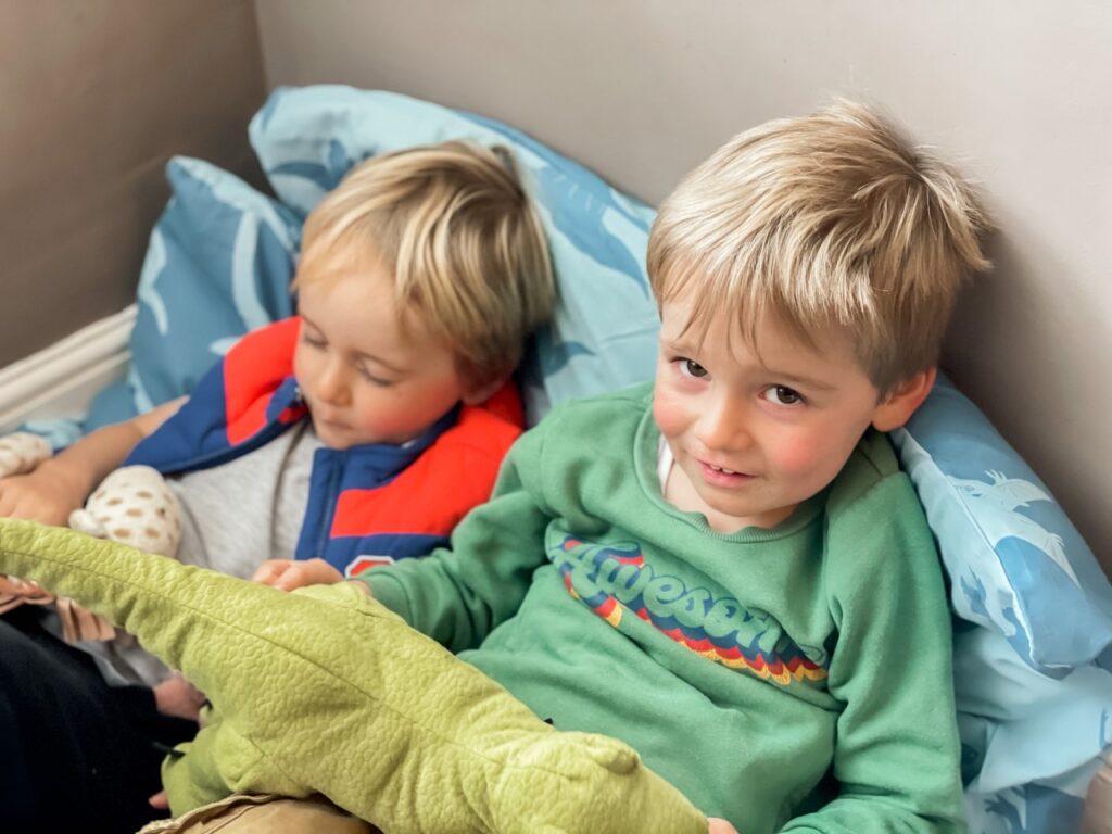 Three year old twin boys under a duvet in a den