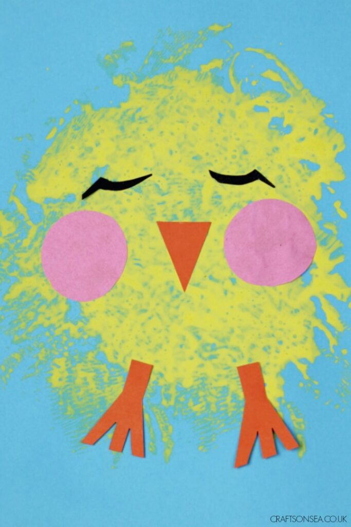 A yellow easter chick made out of sponge painting on a blue background