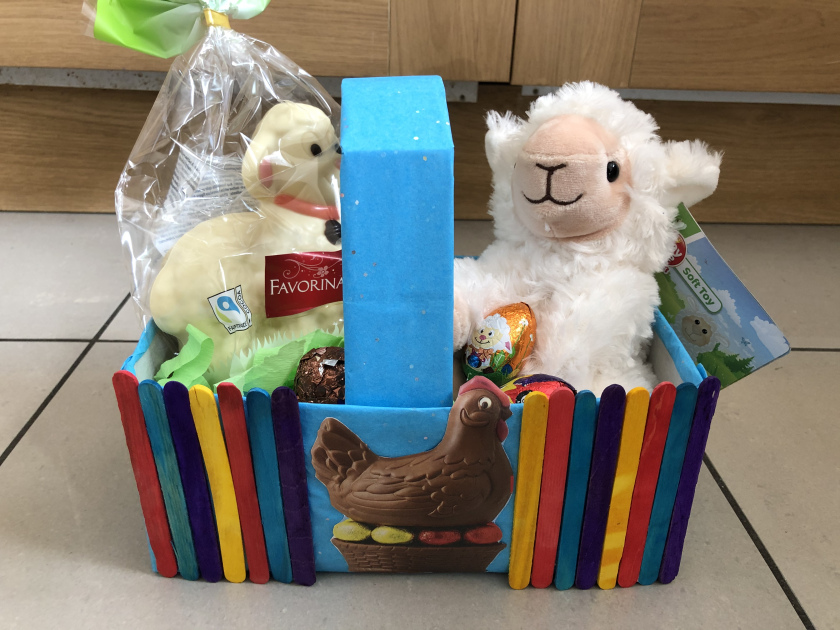 A cuddly sheep and some chocolate inside a homemade easter basket