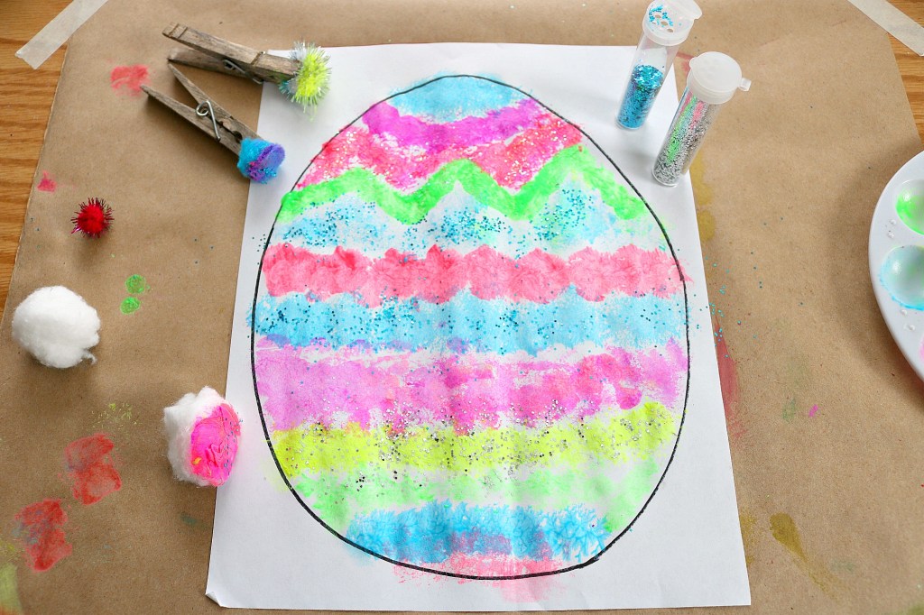 Easter craft idea of using pom poms to paint an outline of an easter egg