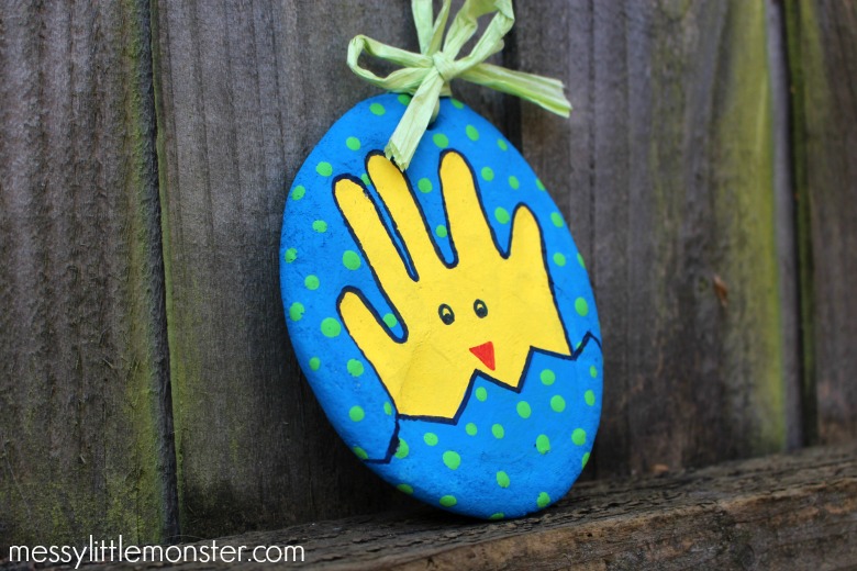 A salt dough decoration with a hand print Easter chick painted yellow on it and a blue spotty background