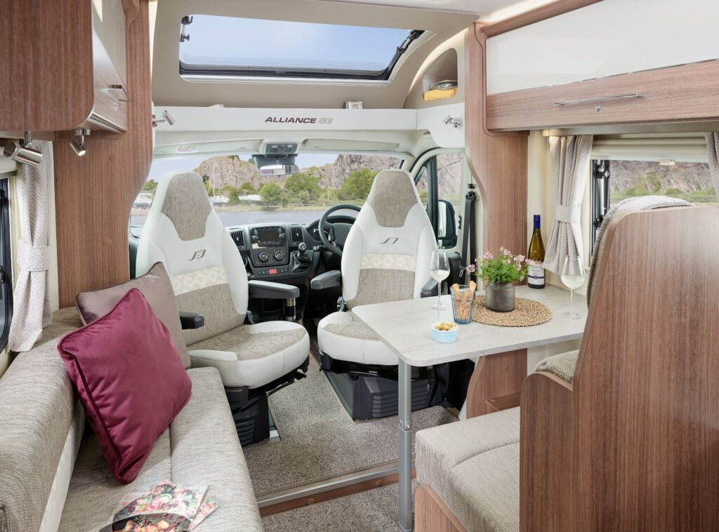 The front part of a motorhome showing the dining, living area and drivers seat