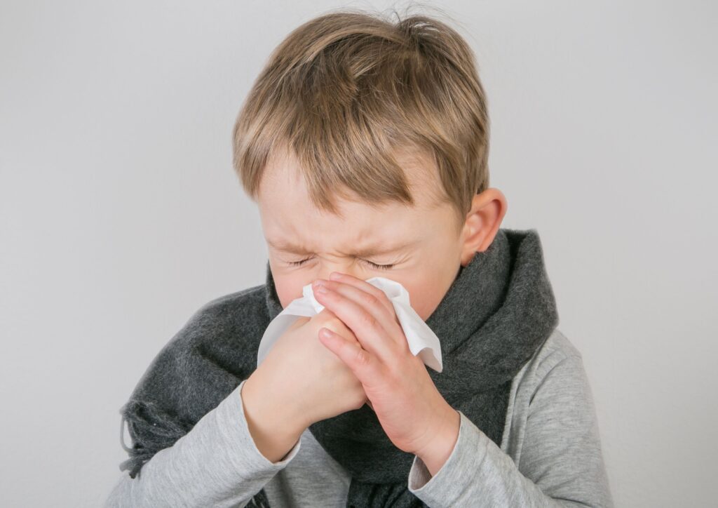 Little boy blowing his nose into a tissue