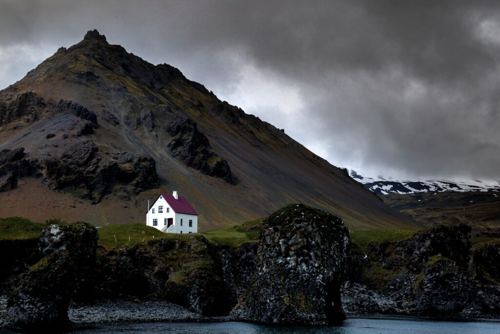 A stormy sky over a mountain and a lone white house in Westfjords in Iceland