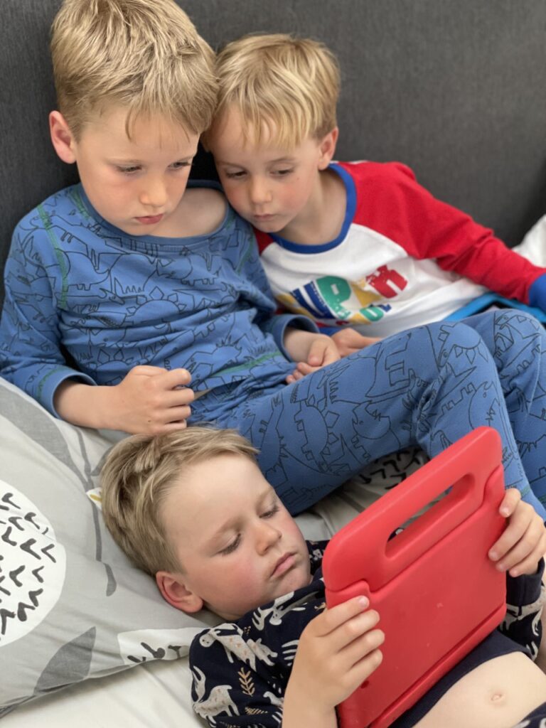 Three brothers in pyjamas crowding round one ipad