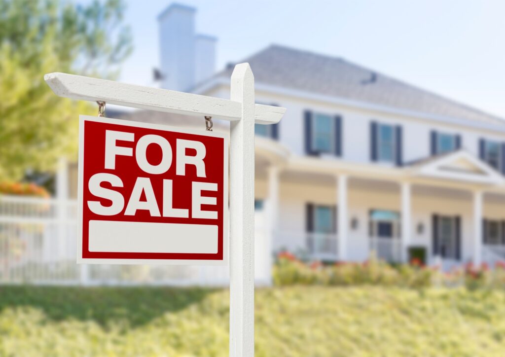 For sale sign on red and white outside a big American style home for a post about buying a house