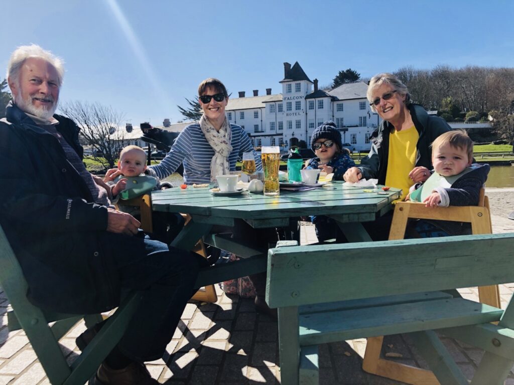 Family with young children and grandparents around an outdoor cafe table