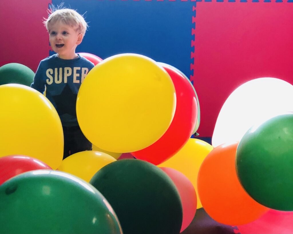 Two year old boy in a room of balloons at the Milky Way