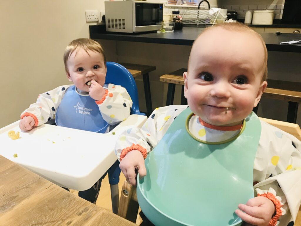 Twin nine month old boys in highchairs at a table