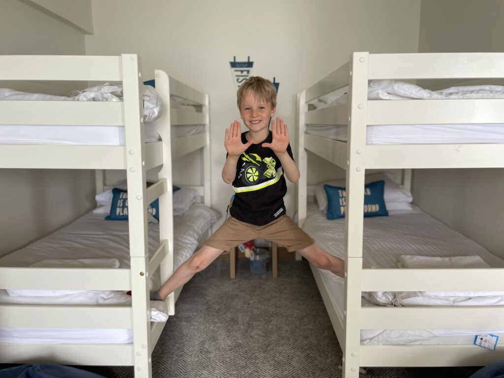 Six year old boy in black t shirt and shorts stands between two bunk beds