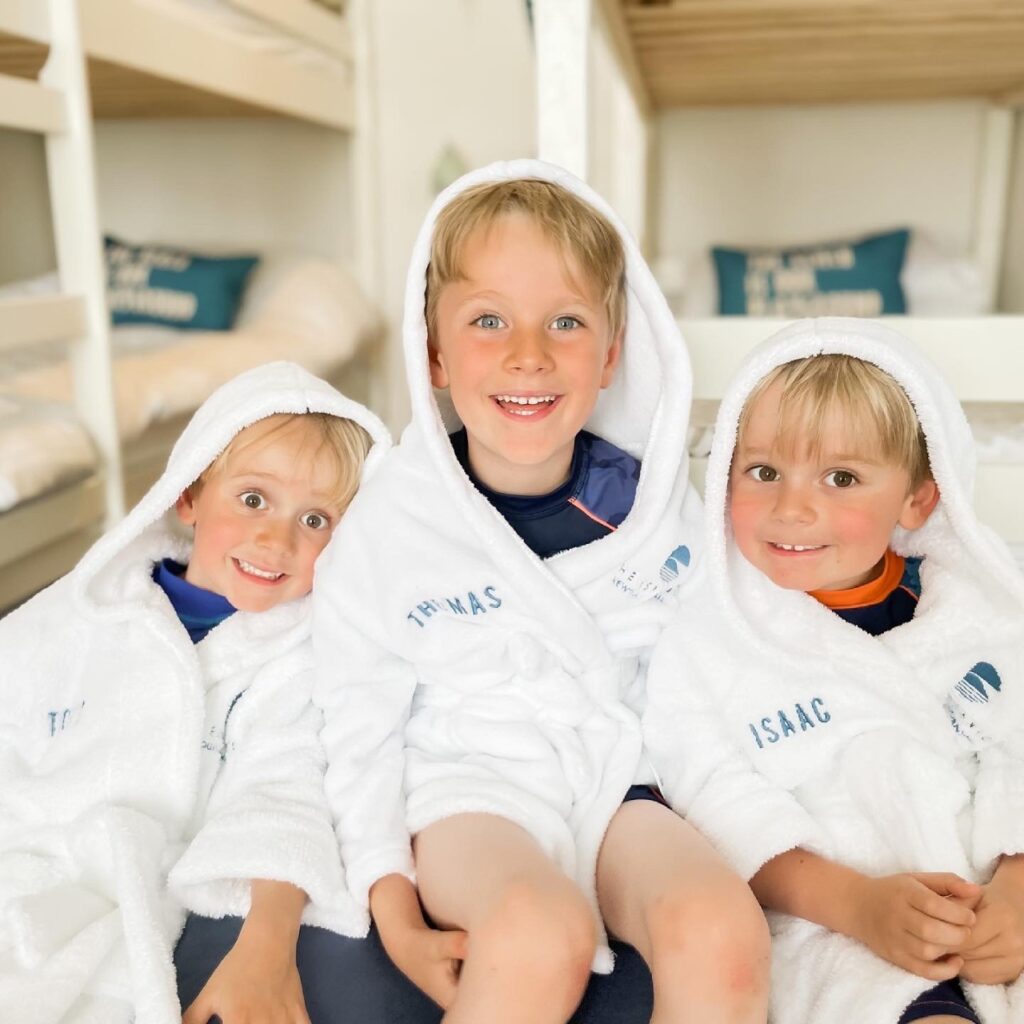 Three young brothers wear white fluffy robes with hoods up