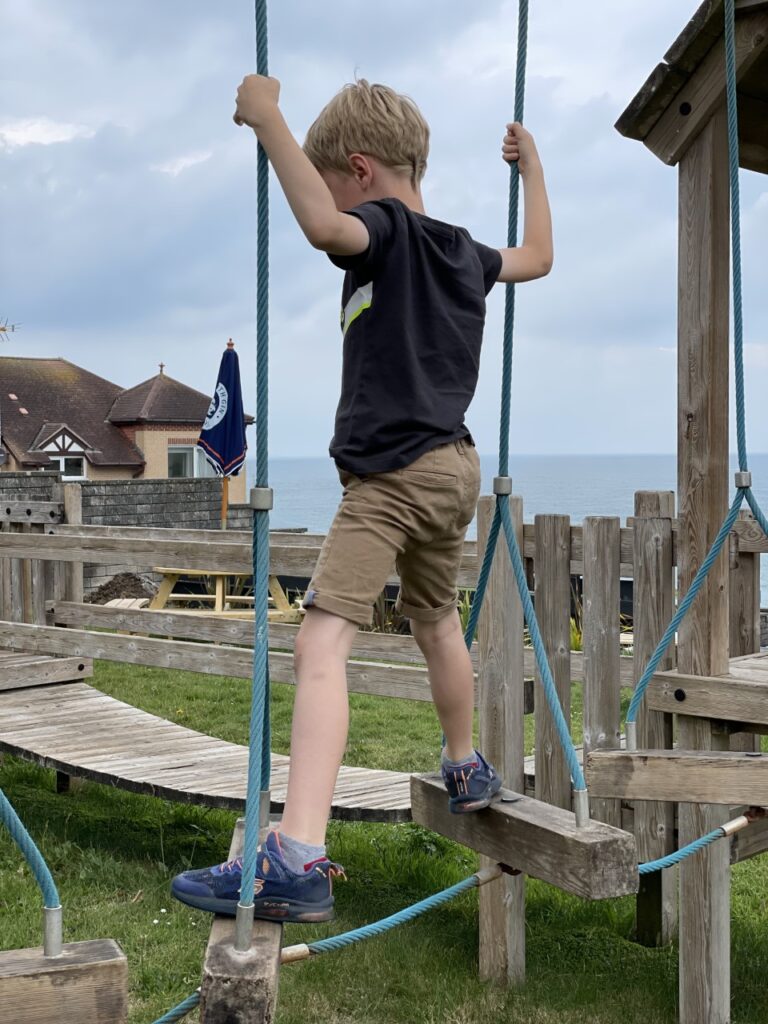 Six year old boy plays on a wooden play area