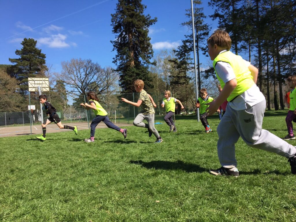 Children play football on a pitch at a summer holiday club