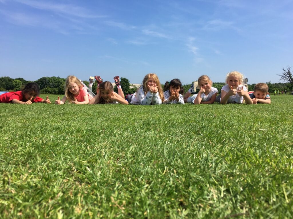 Children lay on the grass at a High 5 summer camp in Plymouth