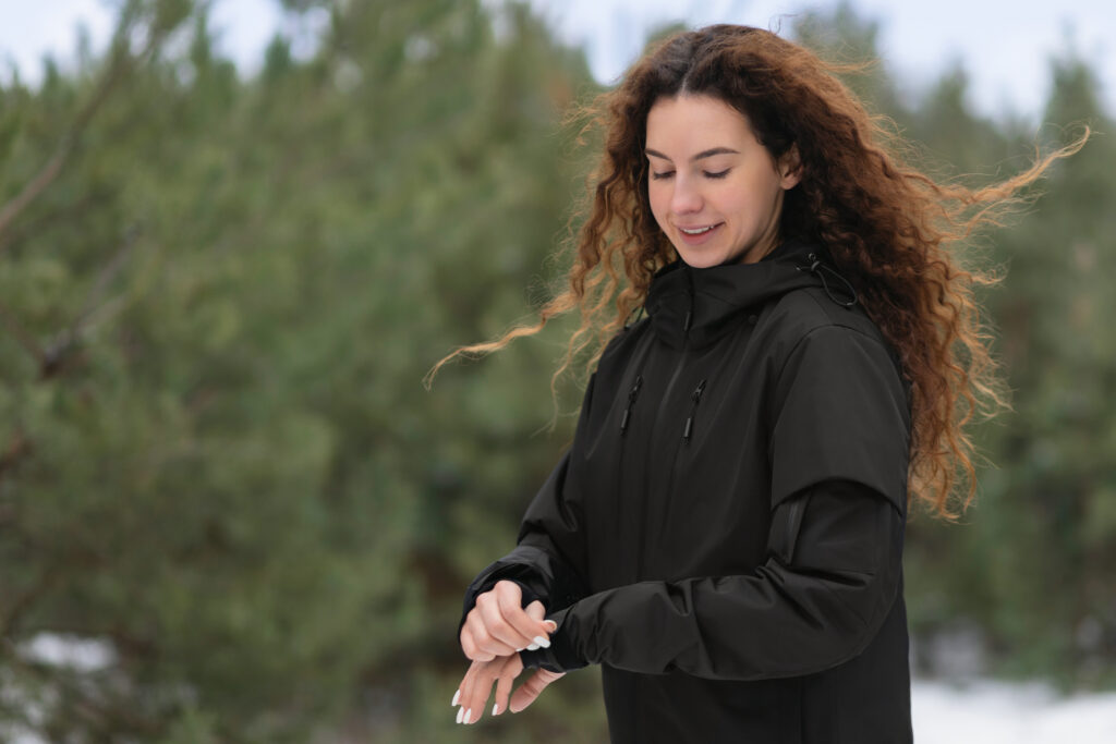 Woman with long dark hair wears a black GAMMA jacket in the woods