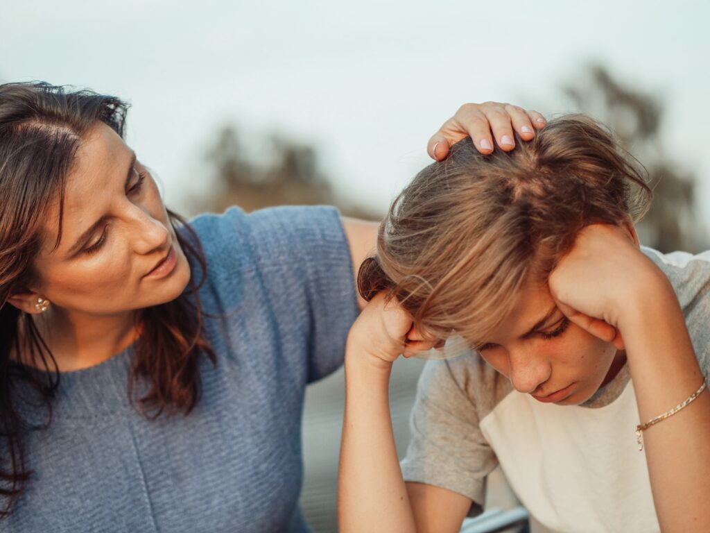 Mum comforting a son with his head his hands talking about sharing custody